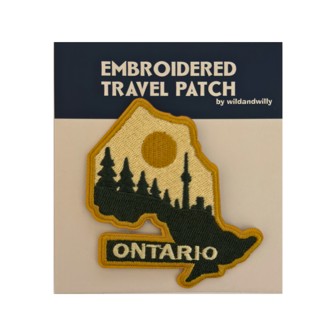 Embroidered travel patch of Ontario with trees and skyline on a beige card.